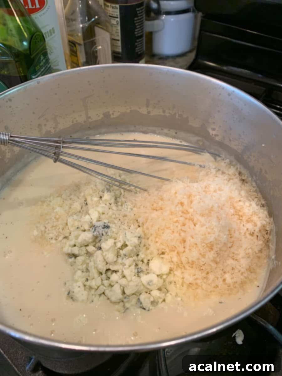 White sauce ingredients in a pan on the stove with a whisk. 