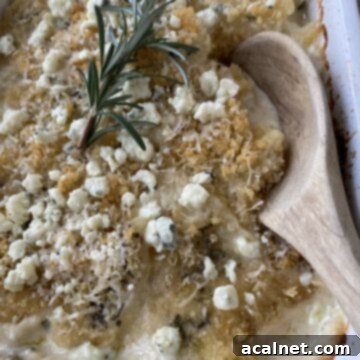 Blue Cheese and Rosemary Scalloped Potatoes baked, with a wooden spoon in the dish for serving.