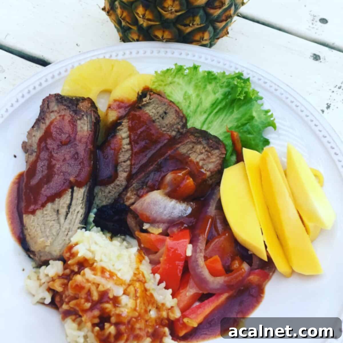 Idaho beef on a plate with rice, mango, red onion, red pepper, pineapple and lettuce.