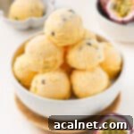 Scoops of ice cream stacked in a white bowl surrounded by fresh passion fruit.