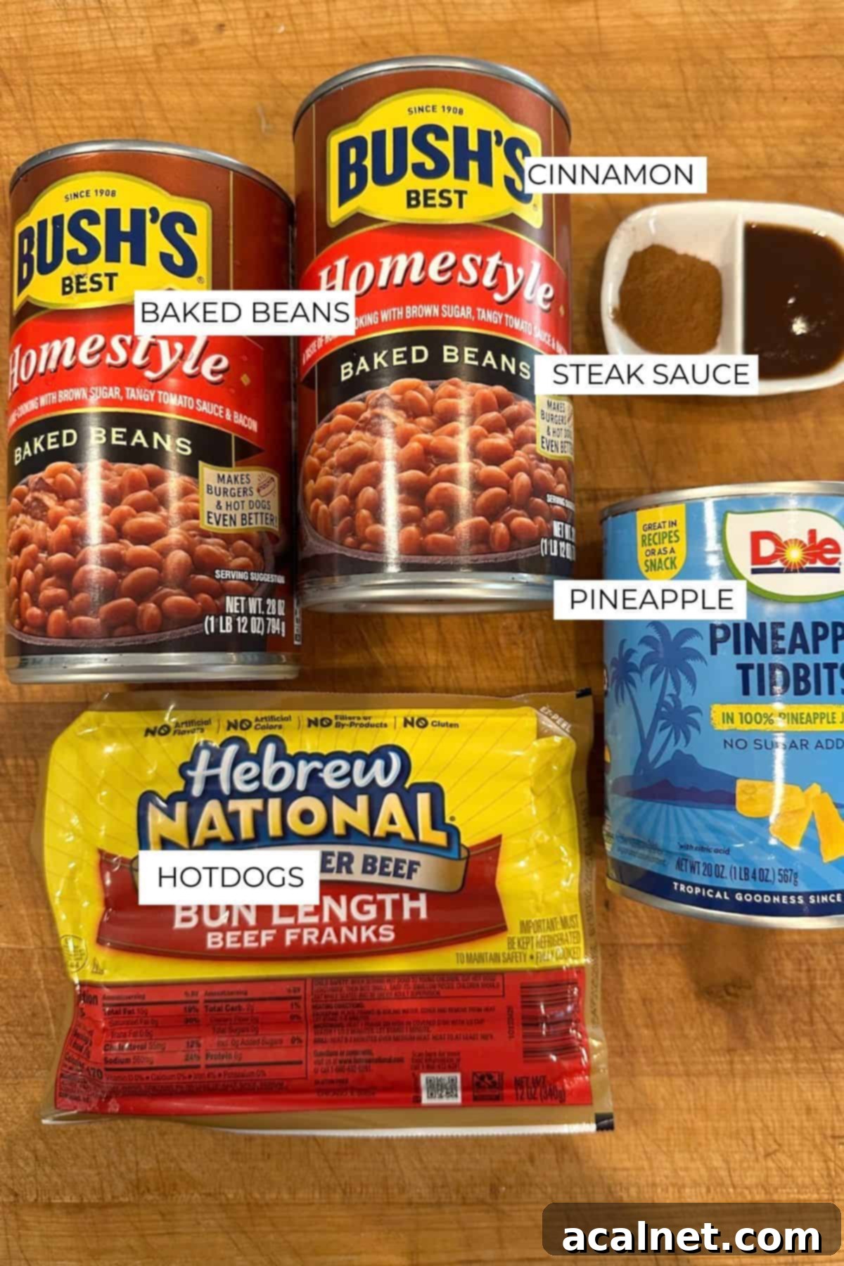 Labeled ingredients for franks and beans laid out on a wooden cutting board.