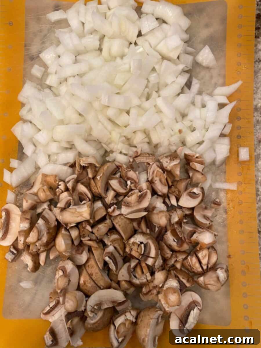Diced mushrooms and onions on a cutting mat.