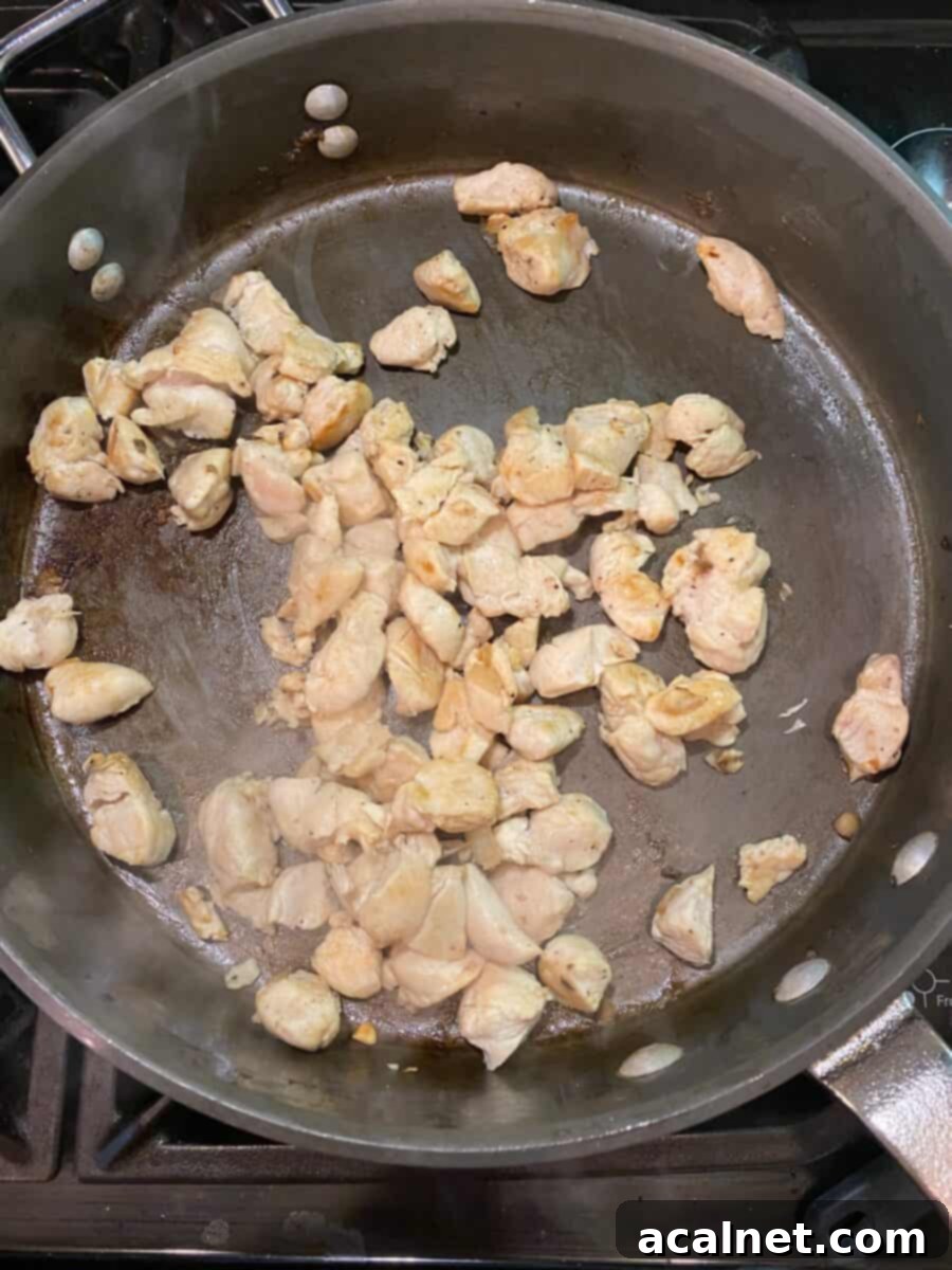 Diced chicken, cooked and in a skillet on the stove.