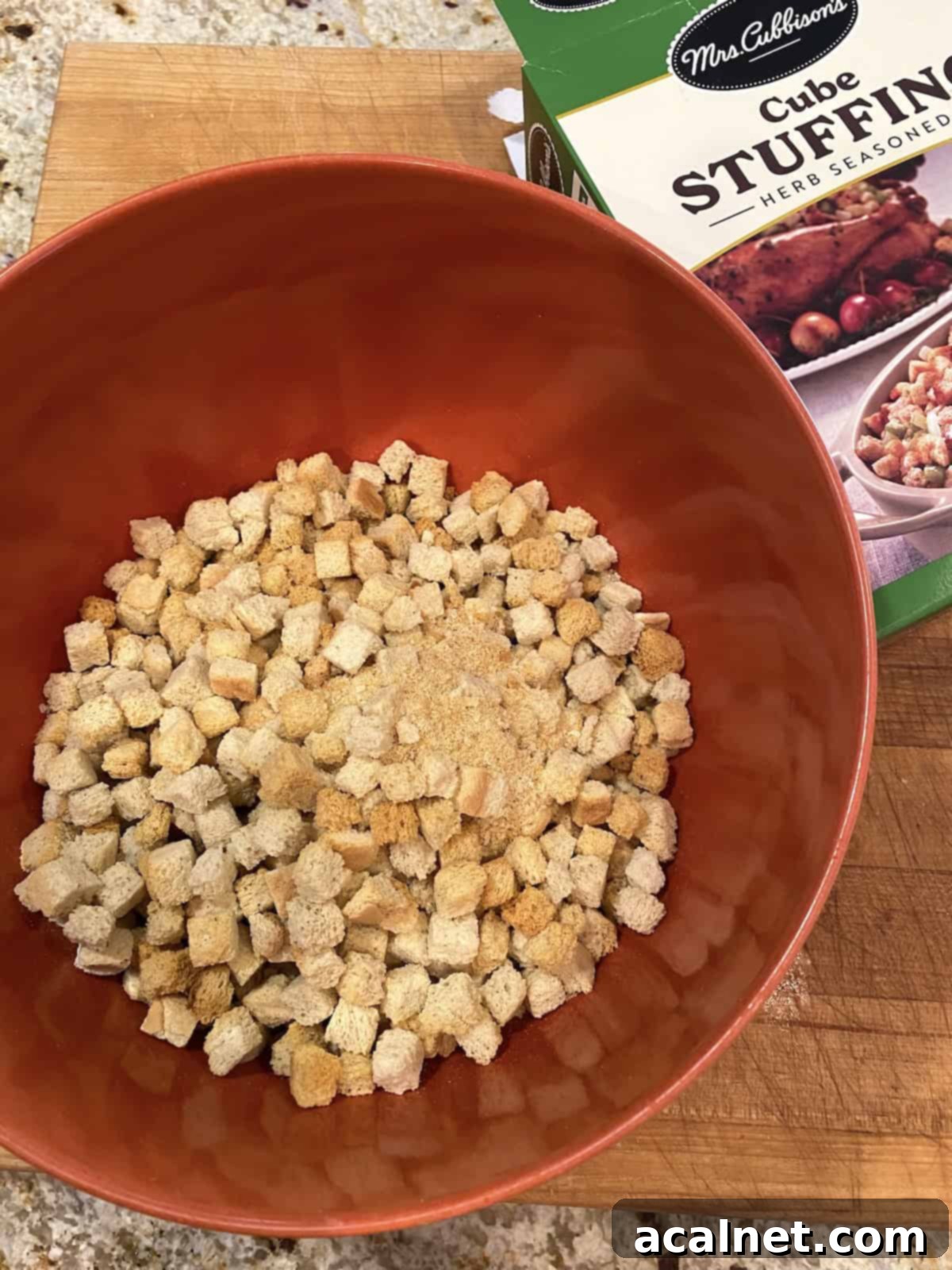 Sweet and Savory Cranberry Apple Stuffing 9 A large mixing bowl containing herb-seasoned cubed stuffing mix.