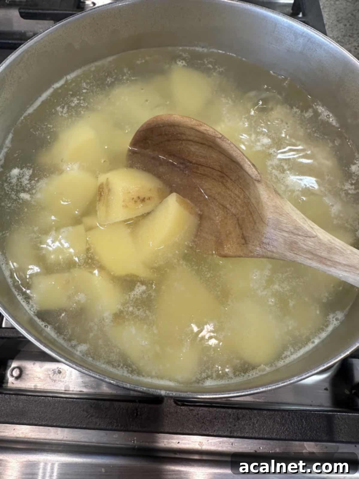 Diced potatoes submerged in boiling water in a large pot on a stove.