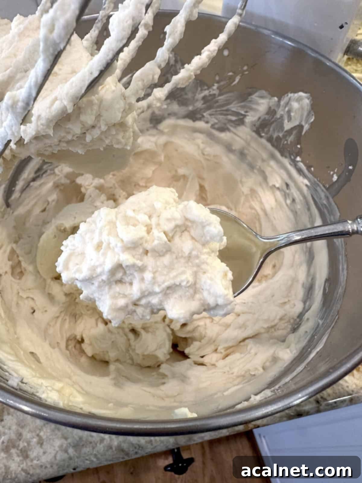 Softened mascarpone cheese, heavy whipping cream, and powdered sugar blended together in a mixing bowl for frosting.