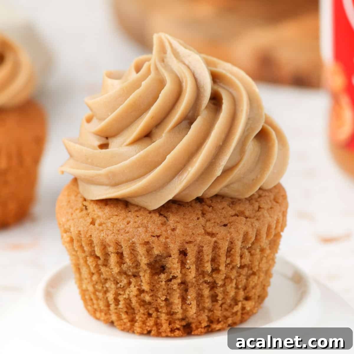 Frosting piped beautifully on a cupcake, elegantly placed in a small white plate.