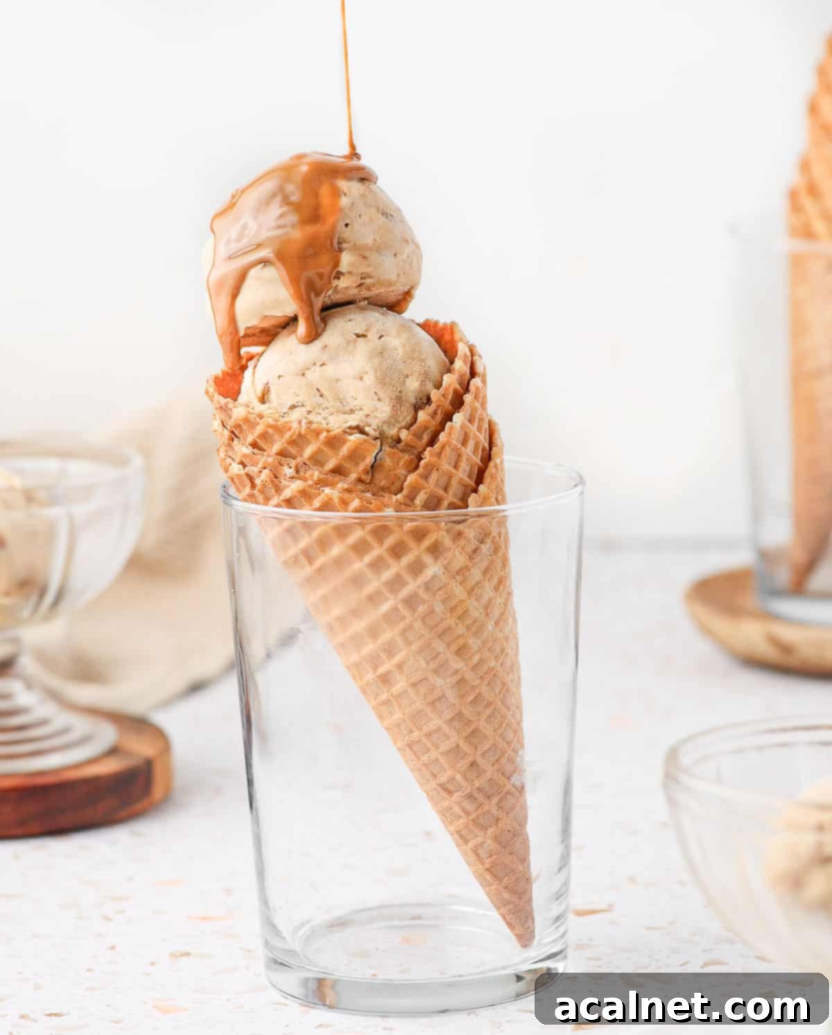 Pouring biscoff spread over the ice cream sitting in a cone.
