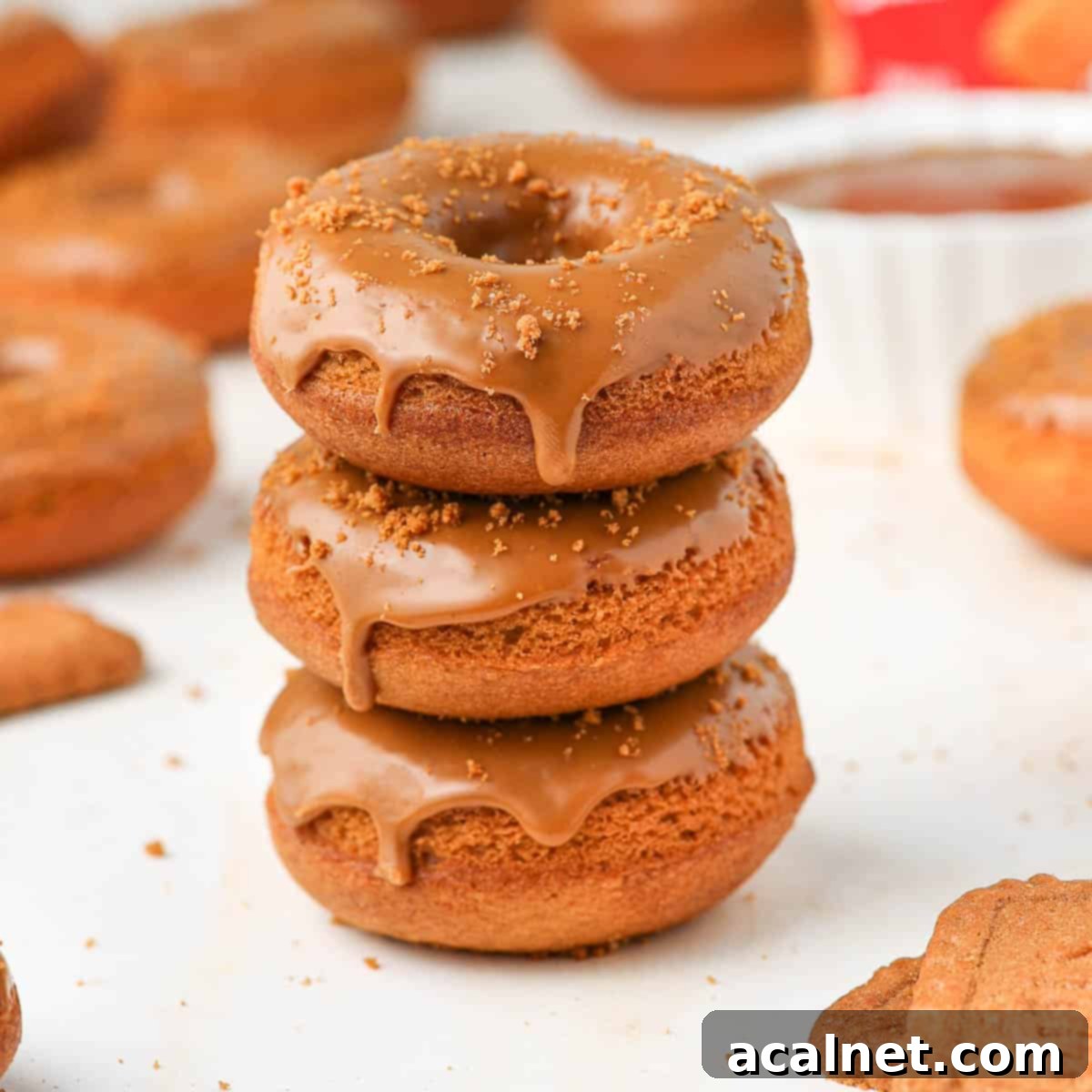 Stack of three Biscoff donuts, beautifully glazed and topped with cookie crumbs.