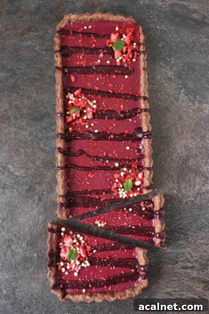 An overhead view of the Chocolate Cherry Tart with a few slices already cut and removed, revealing the deep red cherry curd filling.