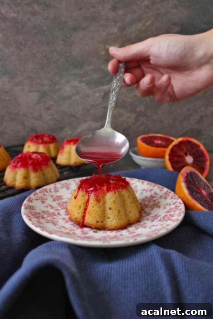 Pouring the blood orange syurp with a sliver spoon over one cake.