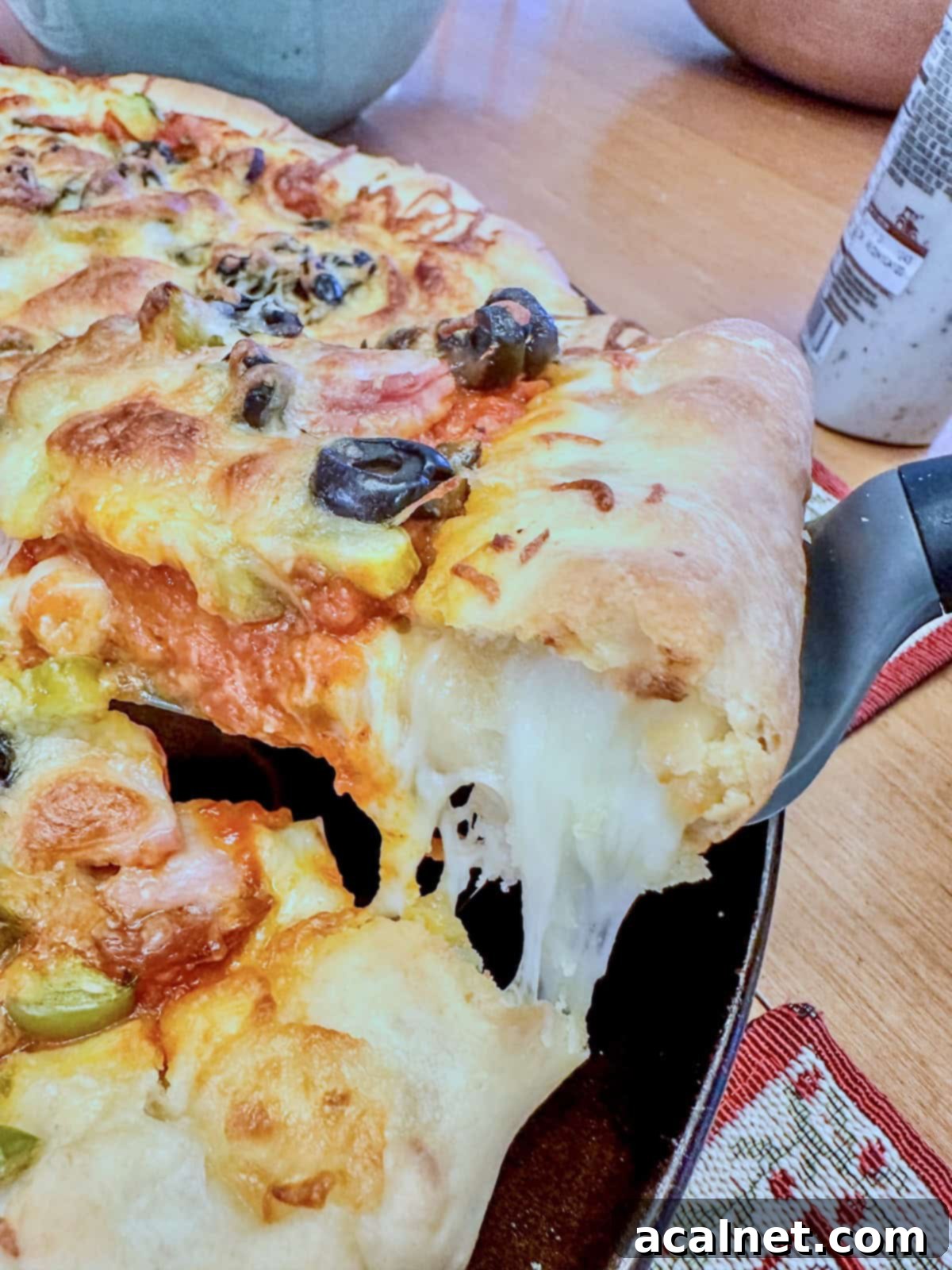 A serving a cheese-stuffed pizza being scooped up,