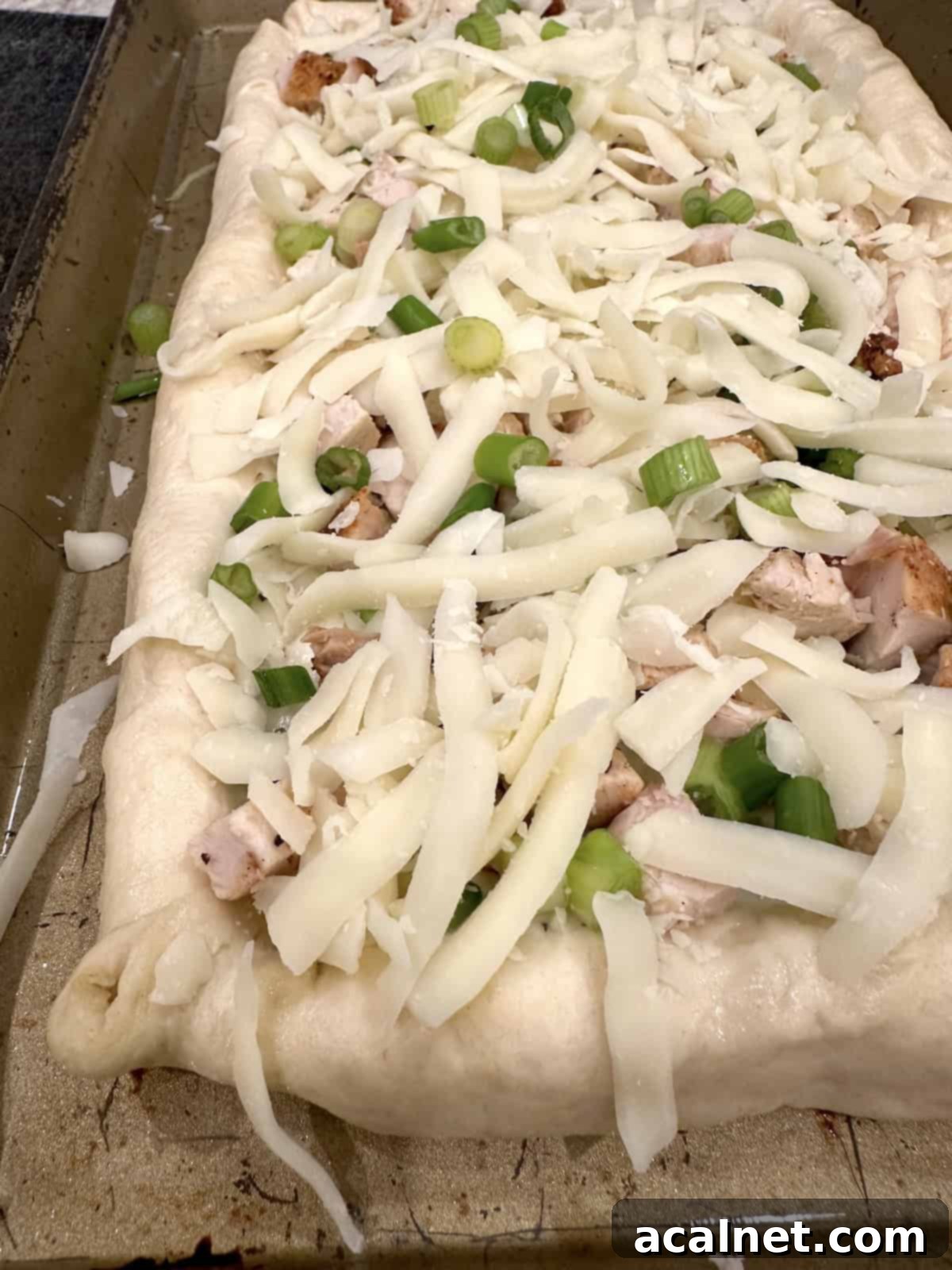 Unbaked pizza with toppings and a cheese stuffed crust.