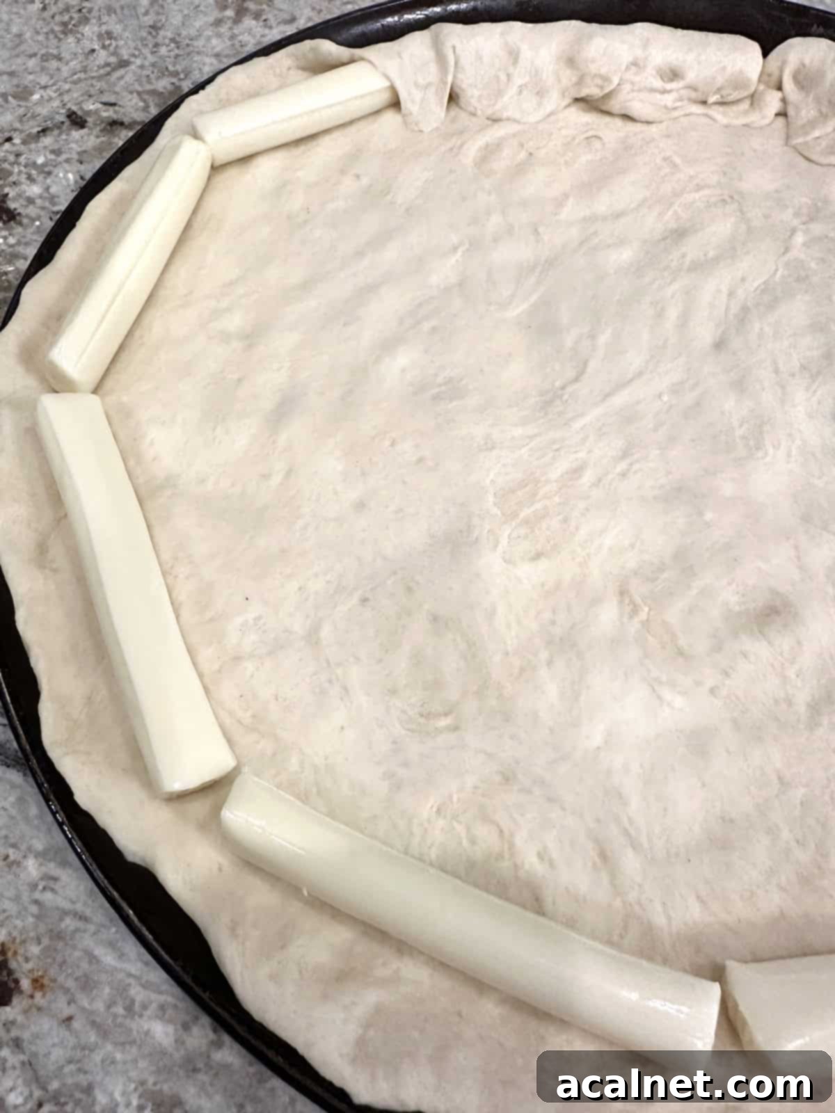 Pizza dough with cheese sticks.