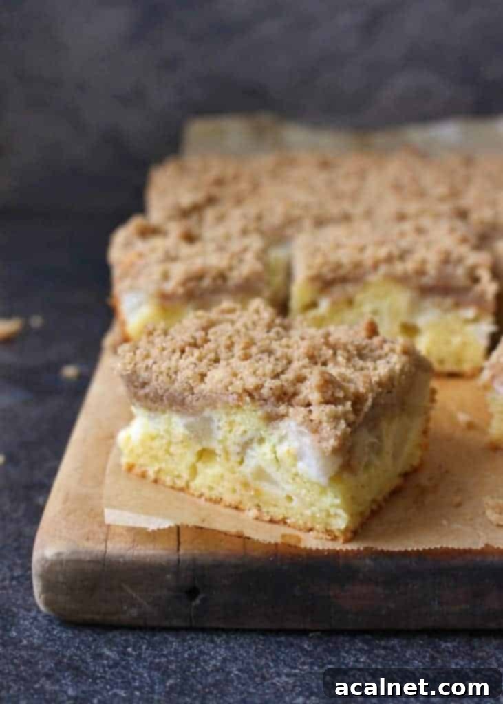 Close-up of a sliced Pear Crumble Cake, revealing the moist interior, succulent juicy pear pieces, and a thick, golden spiced crumb topping.