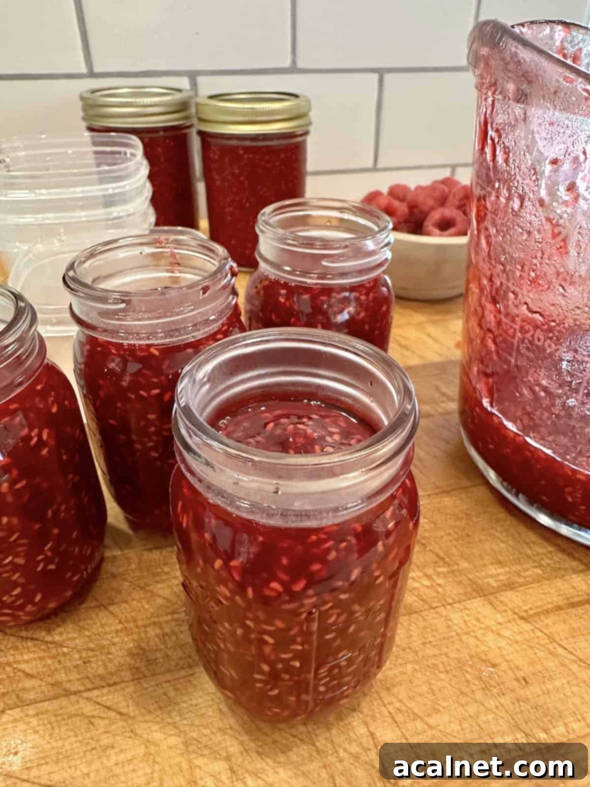 Easy small batch raspberry jam in jars on a cutting board.
