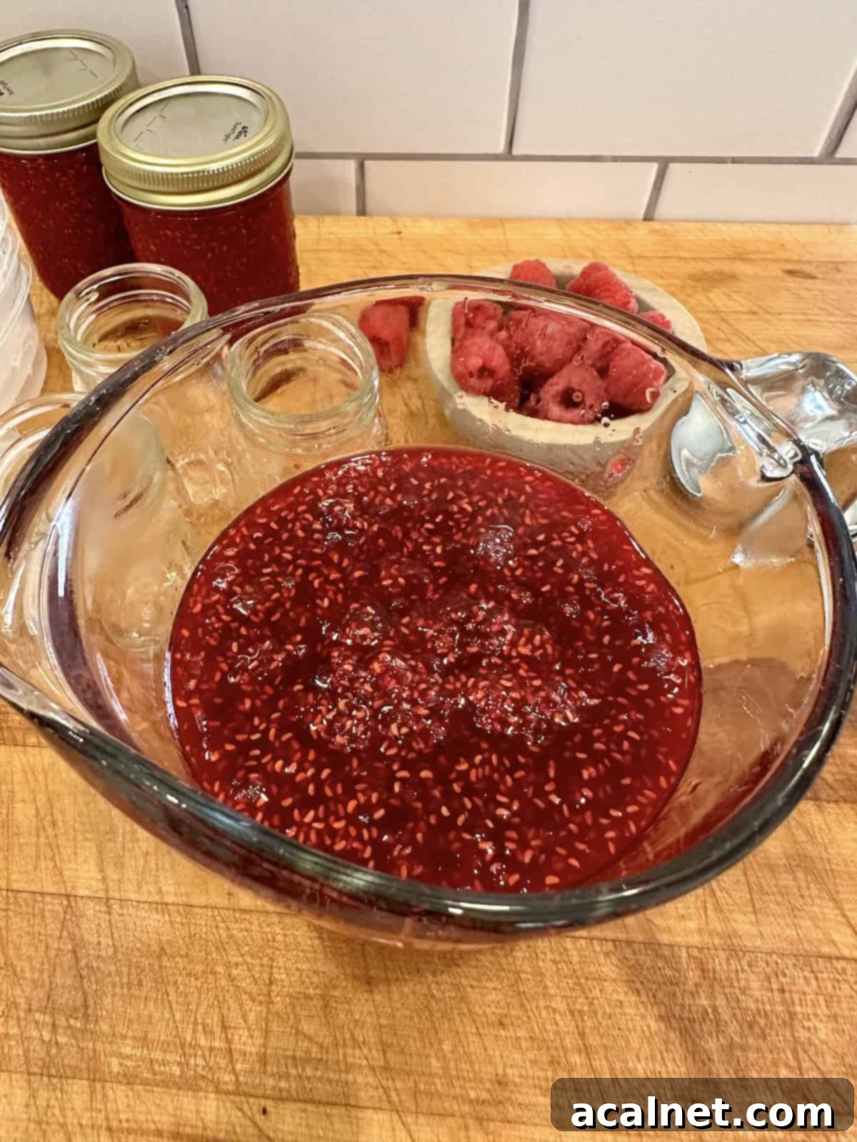Small batch raspberry jam in a glass measuring cup.