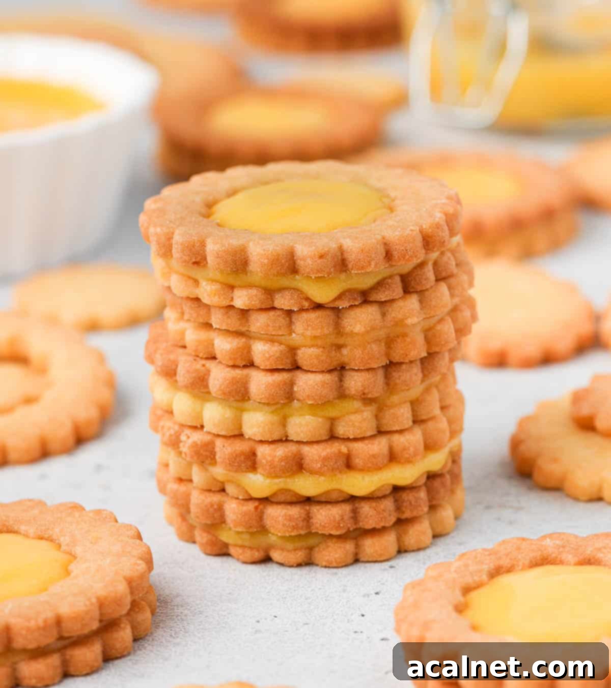 A stack of four perfectly baked lemon curd cookies, showing their layers and golden hue.