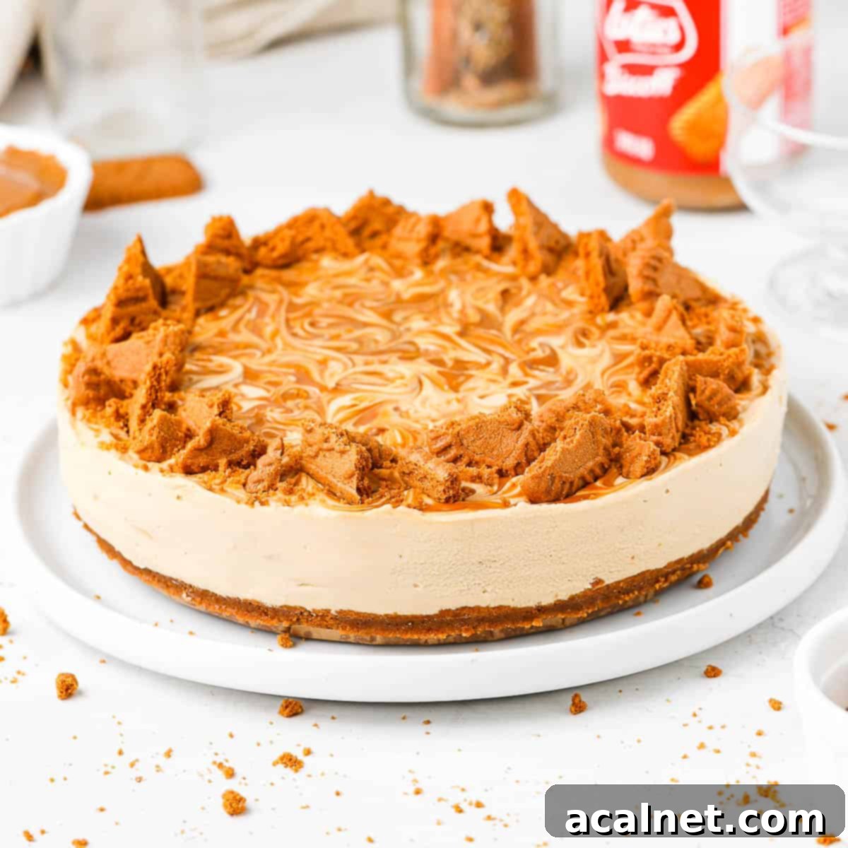 Effortless Biscoff Cheesecake Bliss 2 Decadent No-Bake Biscoff Cheesecake topped with crunchy Biscoff cookie pieces on a white plate, ready to serve.