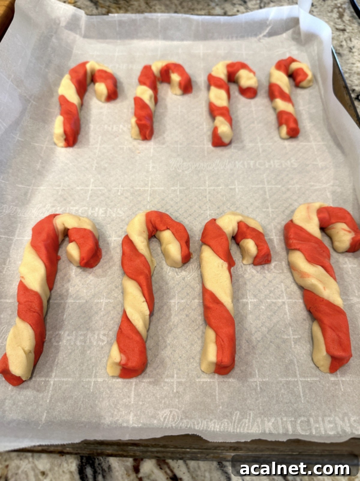 Unbaked candy cane cookies on a baking sheet.