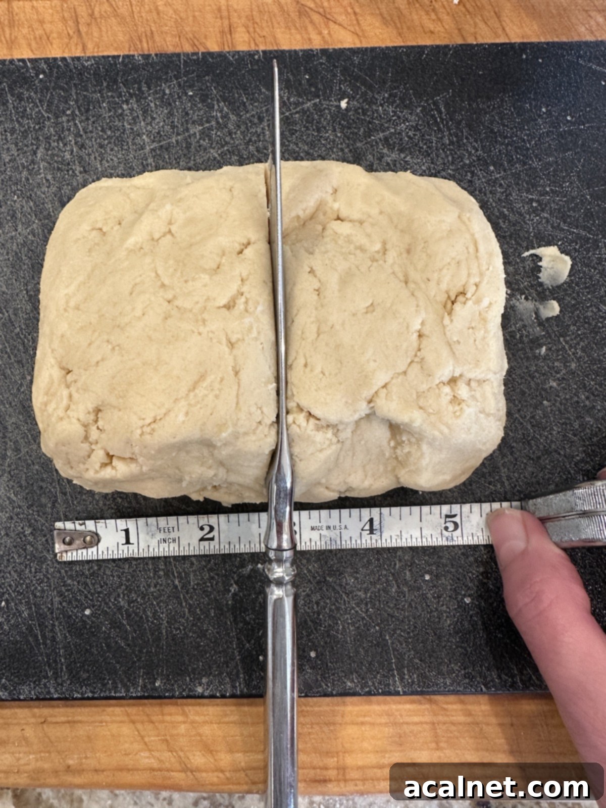 Unbaked holiday cookie dough on a cutting board with a knife and measuring stick.