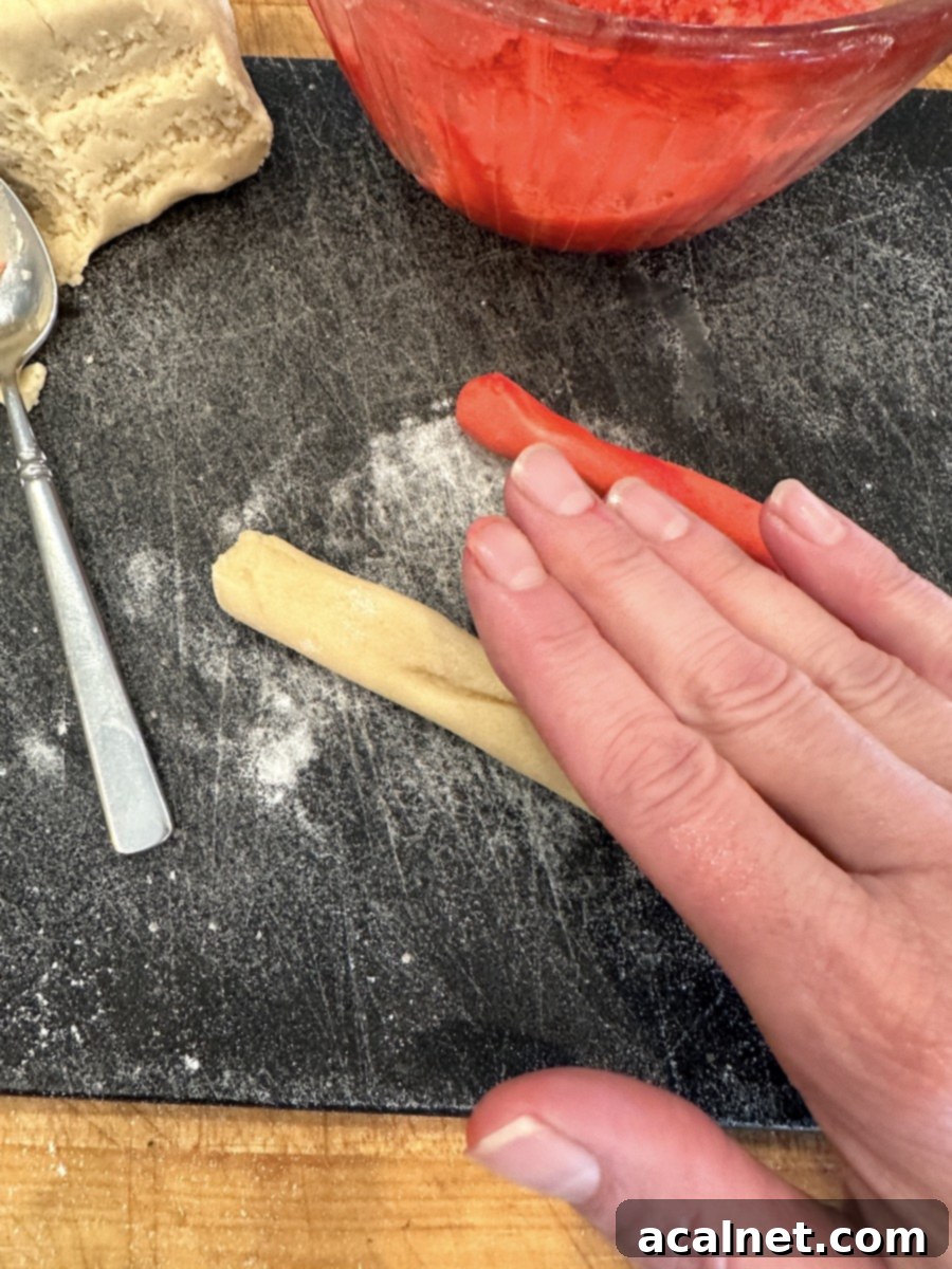 Rolling candy cane cookie dough on a cutting board.
