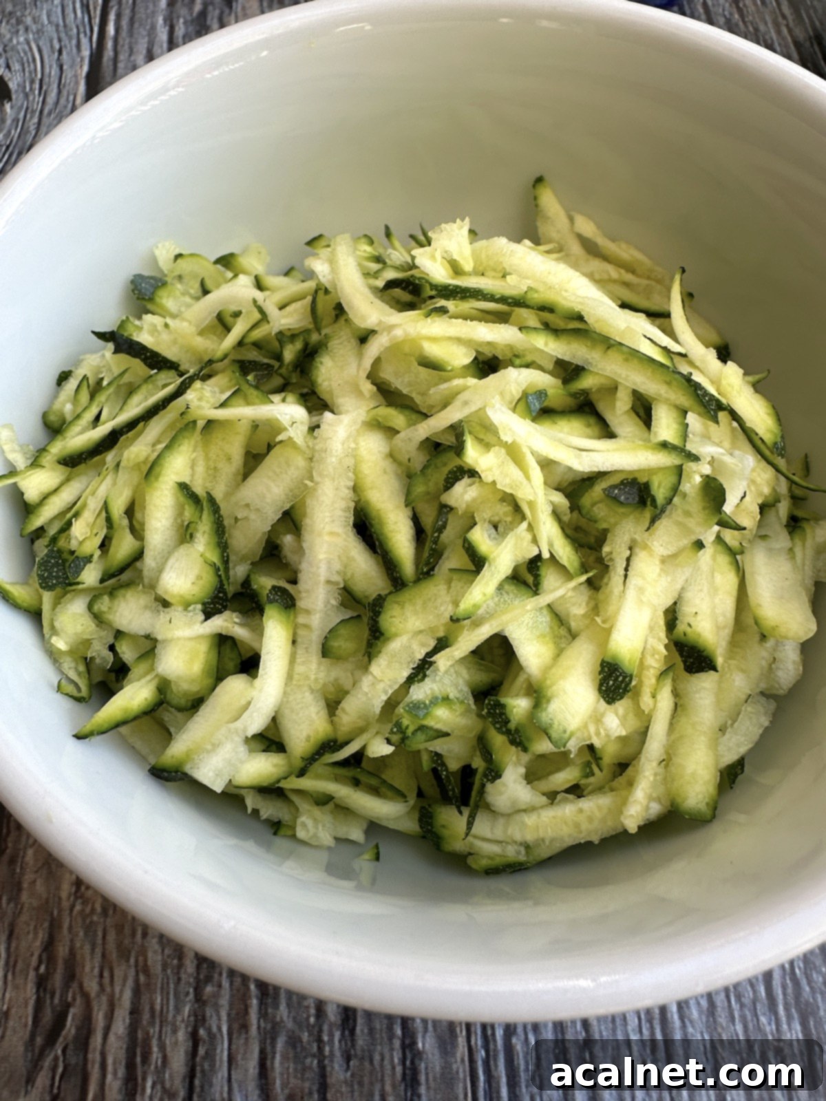 Grated zucchini in a bowl after being blotted, ready to be added to the cake batter.