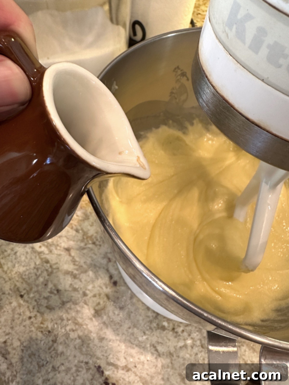 Vanilla extract being added to the creamy mixture of sugar, oil, and butter.