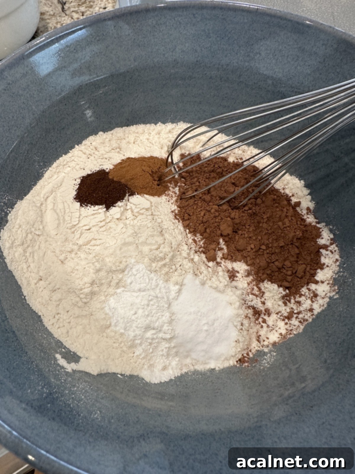 Dry ingredients for chocolate zucchini cake, including flour, cocoa, and spices, measured into a bowl.
