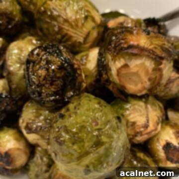 Maple and balsamic drenched Brussels sprouts mounded on a serving plate, fresh from the oven.