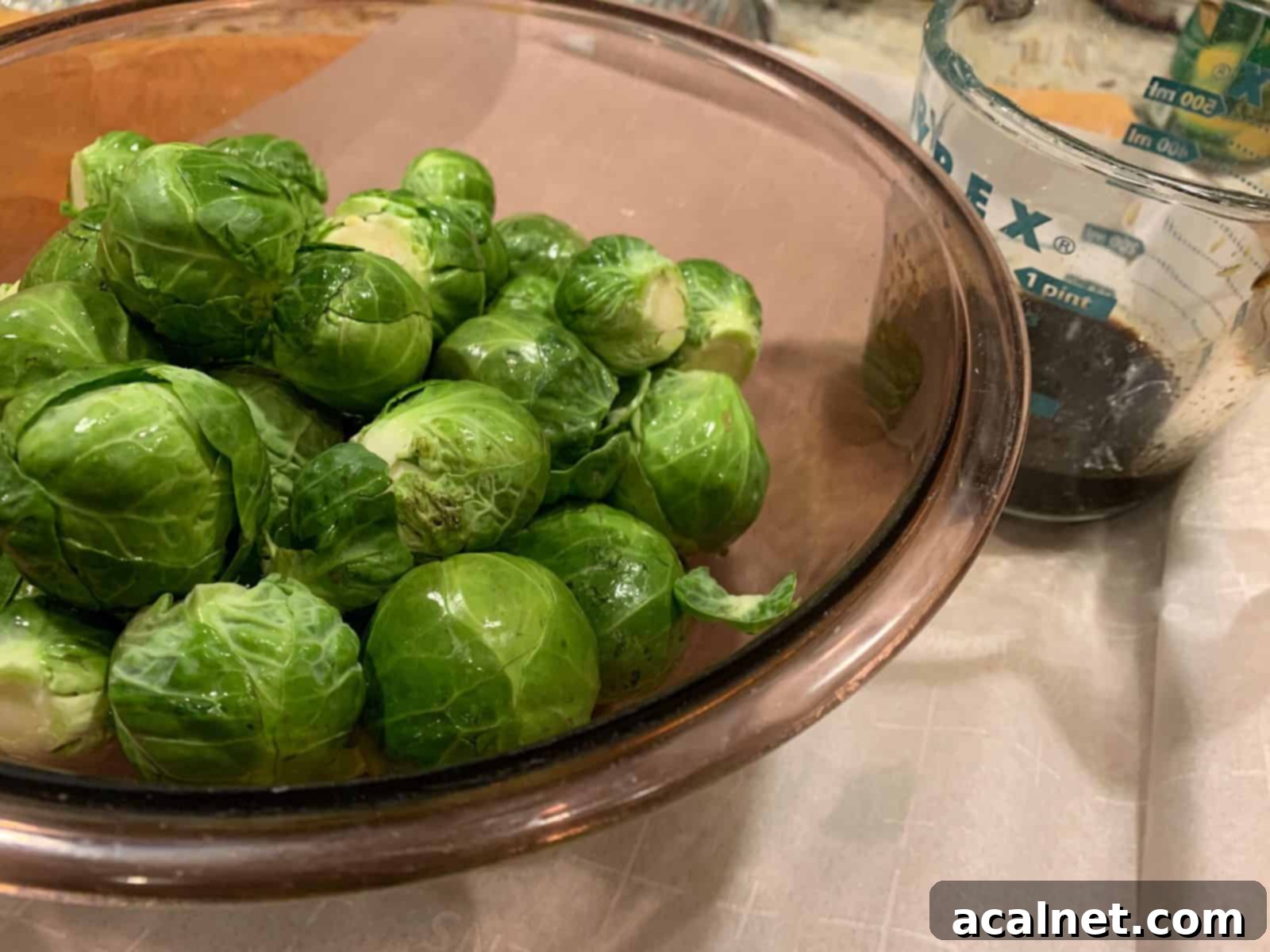 Veggies in a mixing bowl with vinegar and maple syrup mixture on the side, showing the ingredients for the glaze.