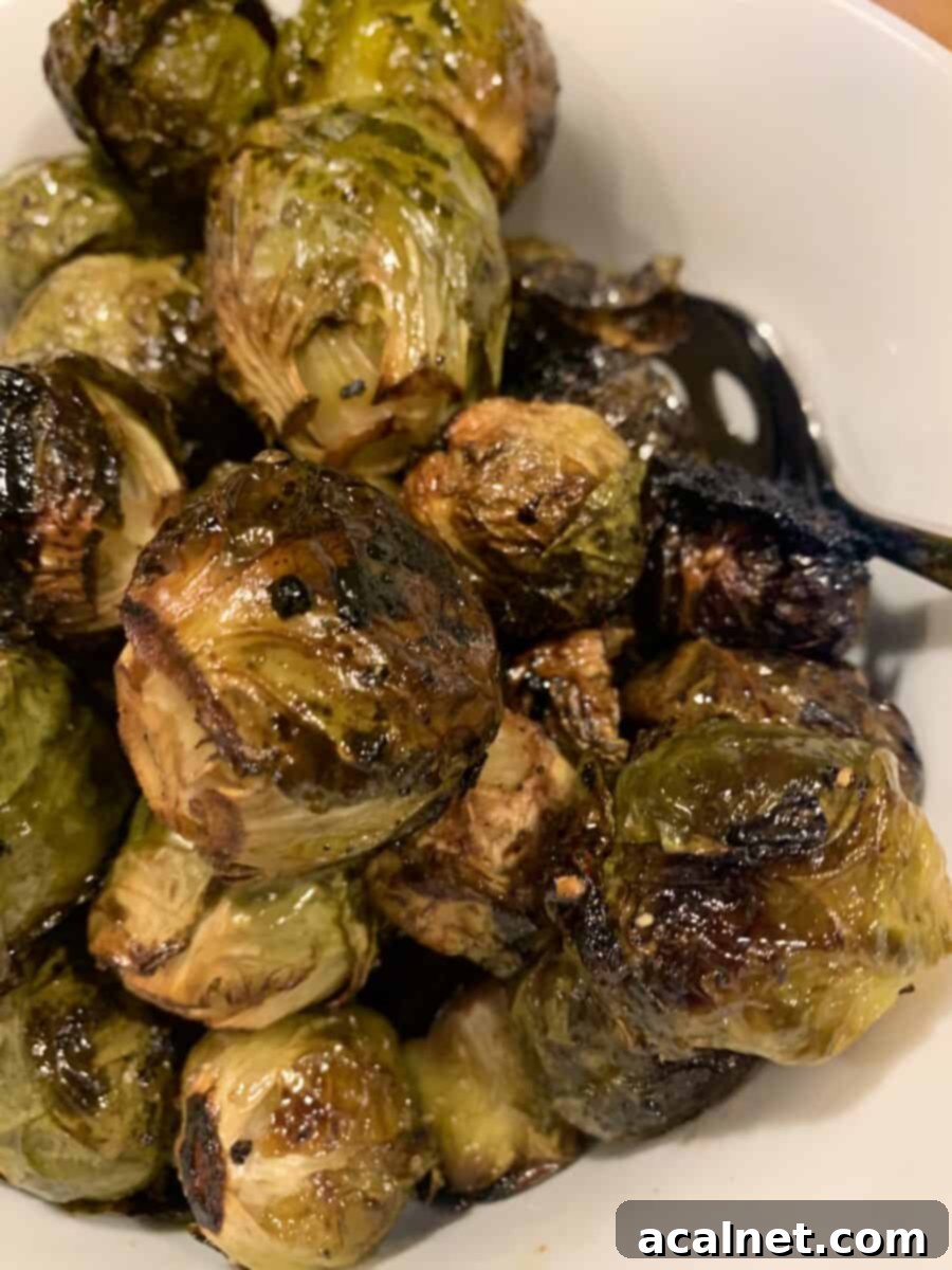 Whole, glazed Brussels sprouts mounded on a serving bowl after roasting, ready to be enjoyed.