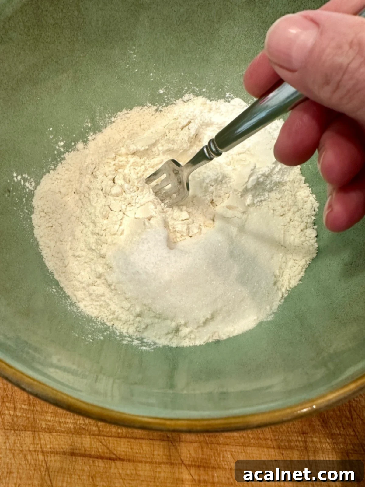 Dry ingredients for homemade biscuits in a bowl with a fork, showing the initial mixing stage.