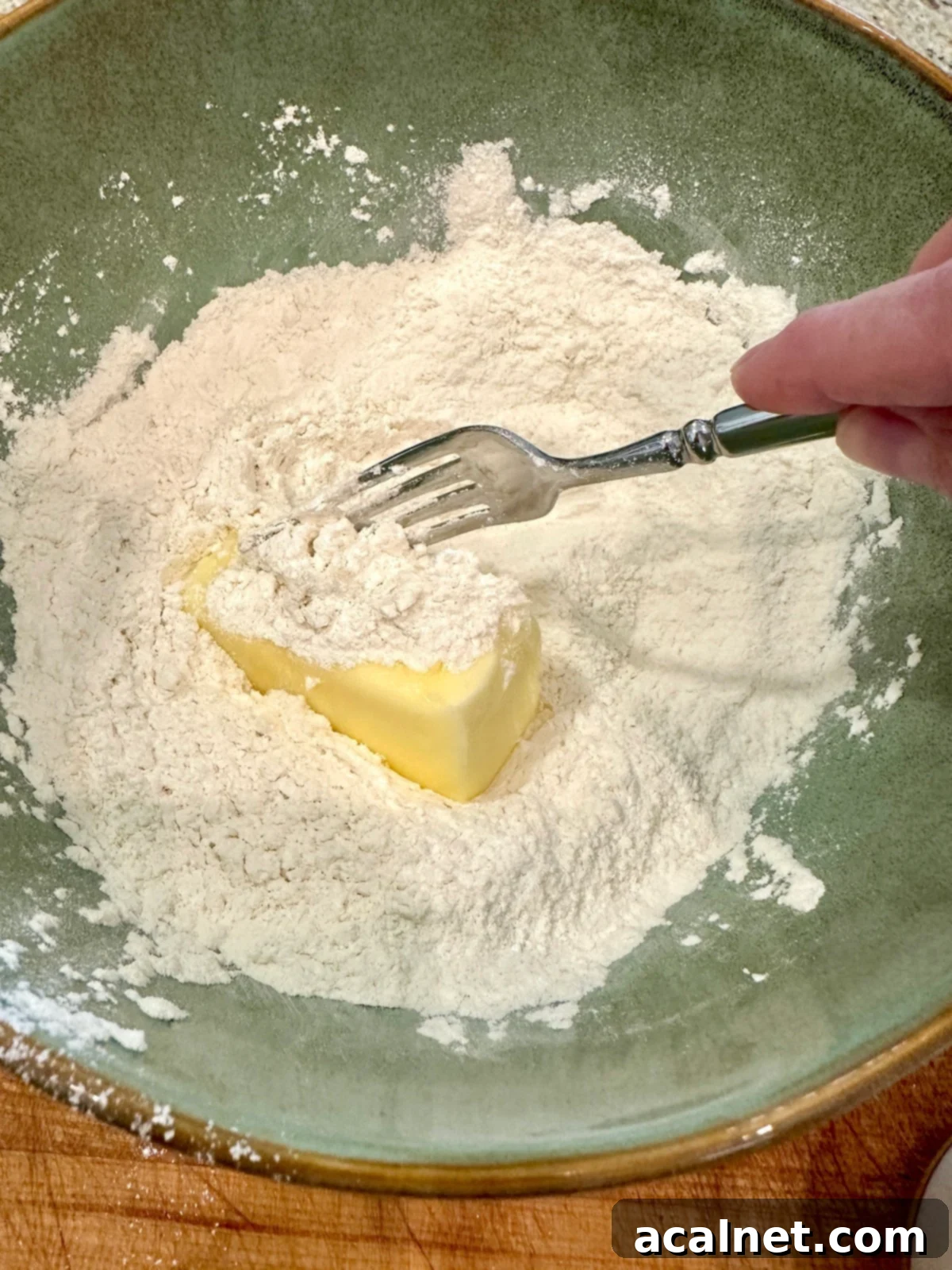 Dry ingredients with softened butter in a bowl, being mixed to a crumbly consistency.