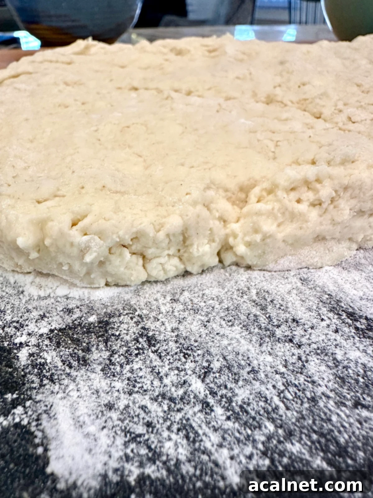 Homemade biscuit dough rolled out on a floured cutting board, ready for cutting.