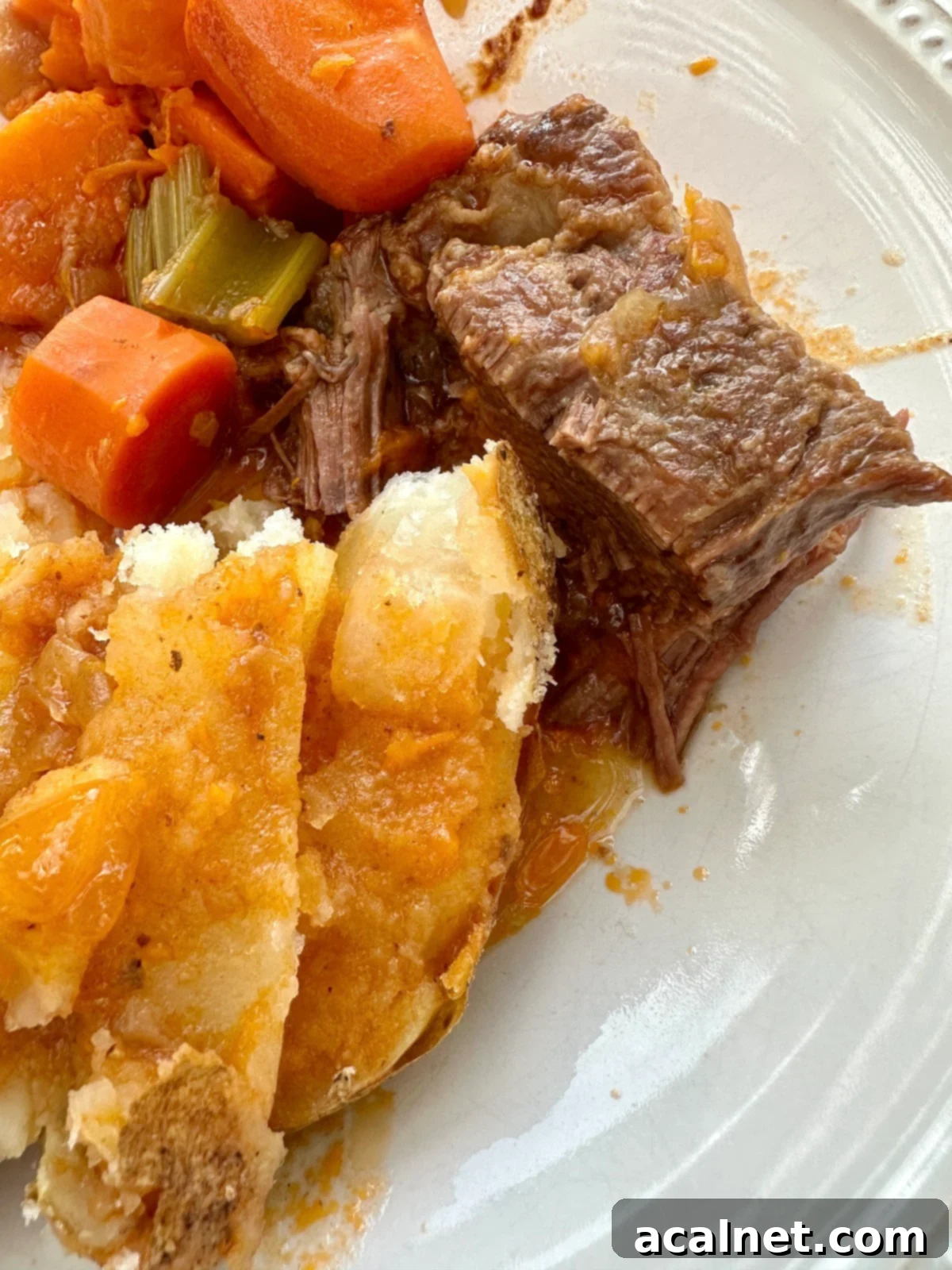 Dutch oven pot roast on a plate with vegetables and potato.