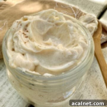 Homemade honey butter in a small jar, garnished with a wooden spoon and a rustic setting.