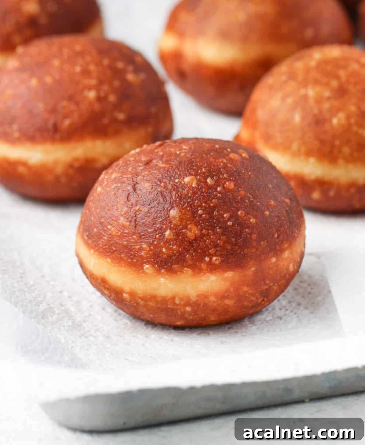 Gourmet Brioche Delights 7 Freshly fried brioche donuts draining on paper towels over a baking tray.