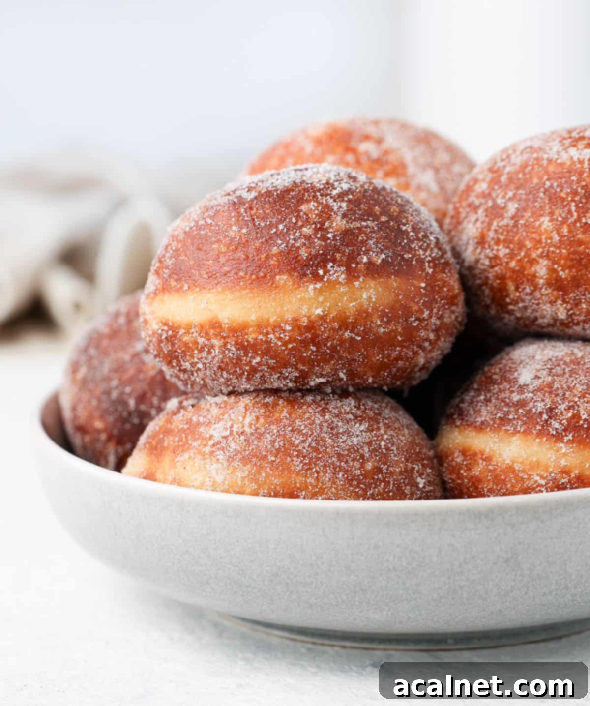 Gourmet Brioche Delights 8 Close-up shot of a stack of fluffy brioche donuts nestled in a large grey serving bowl, invitingly golden and ready to be enjoyed.