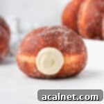 Decadent Bavarian Cream Doughnuts 11 Close up on one donut with piped cream coming out.