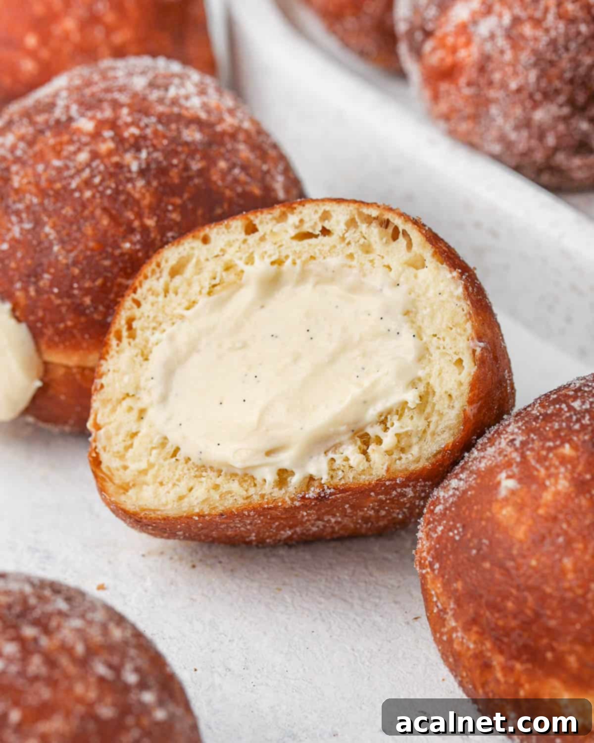 Decadent Bavarian Cream Doughnuts 8 Donut sliced in half placed between full donuts.