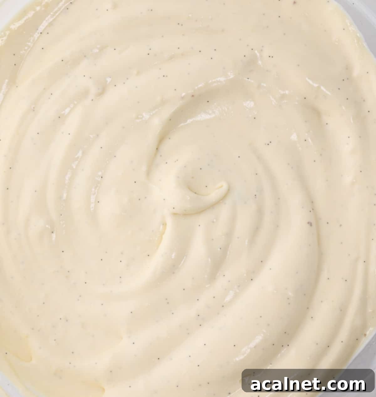 A close-up, top-down view of smooth, creamy Bavarian Cream in a mixing bowl, showcasing its perfect texture.