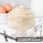 Cream piped in a glass cup surrounded by vanilla bean, eggs and milk.