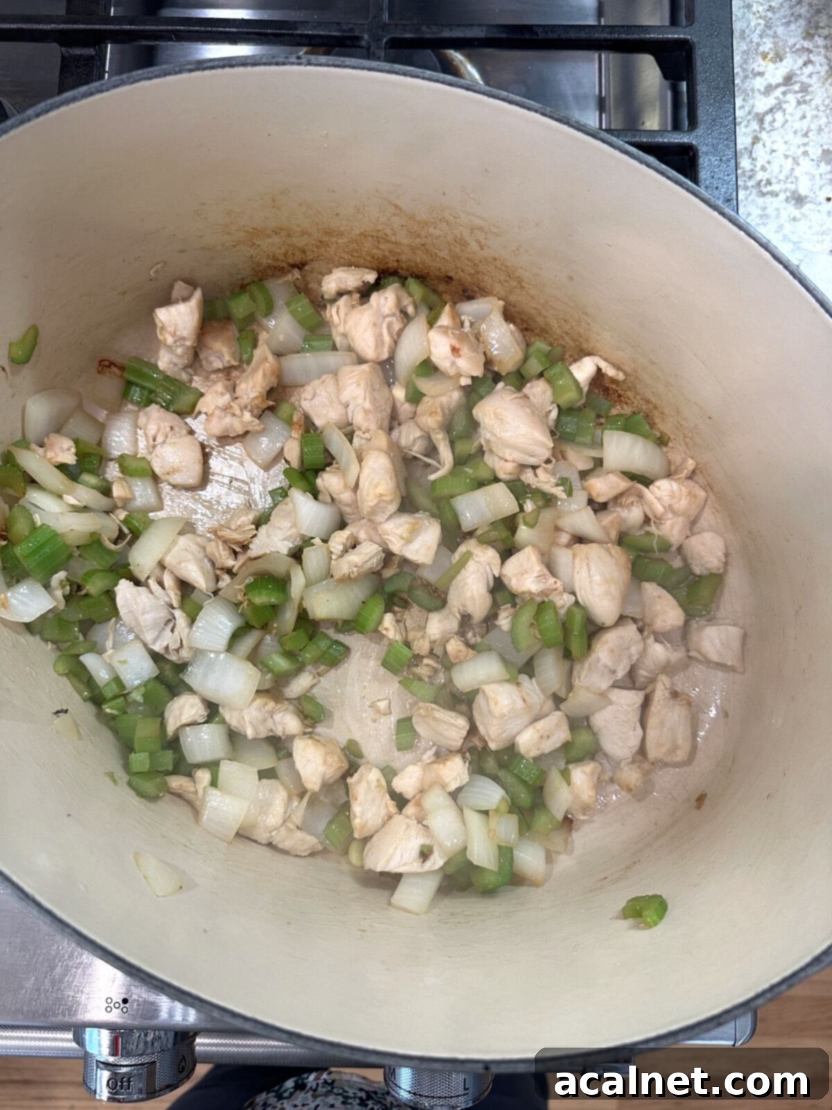 Golden Harvest Chowder 6 Diced chicken, celery, and onions sautéing together in a large pan on the stove, releasing aromatic flavors.