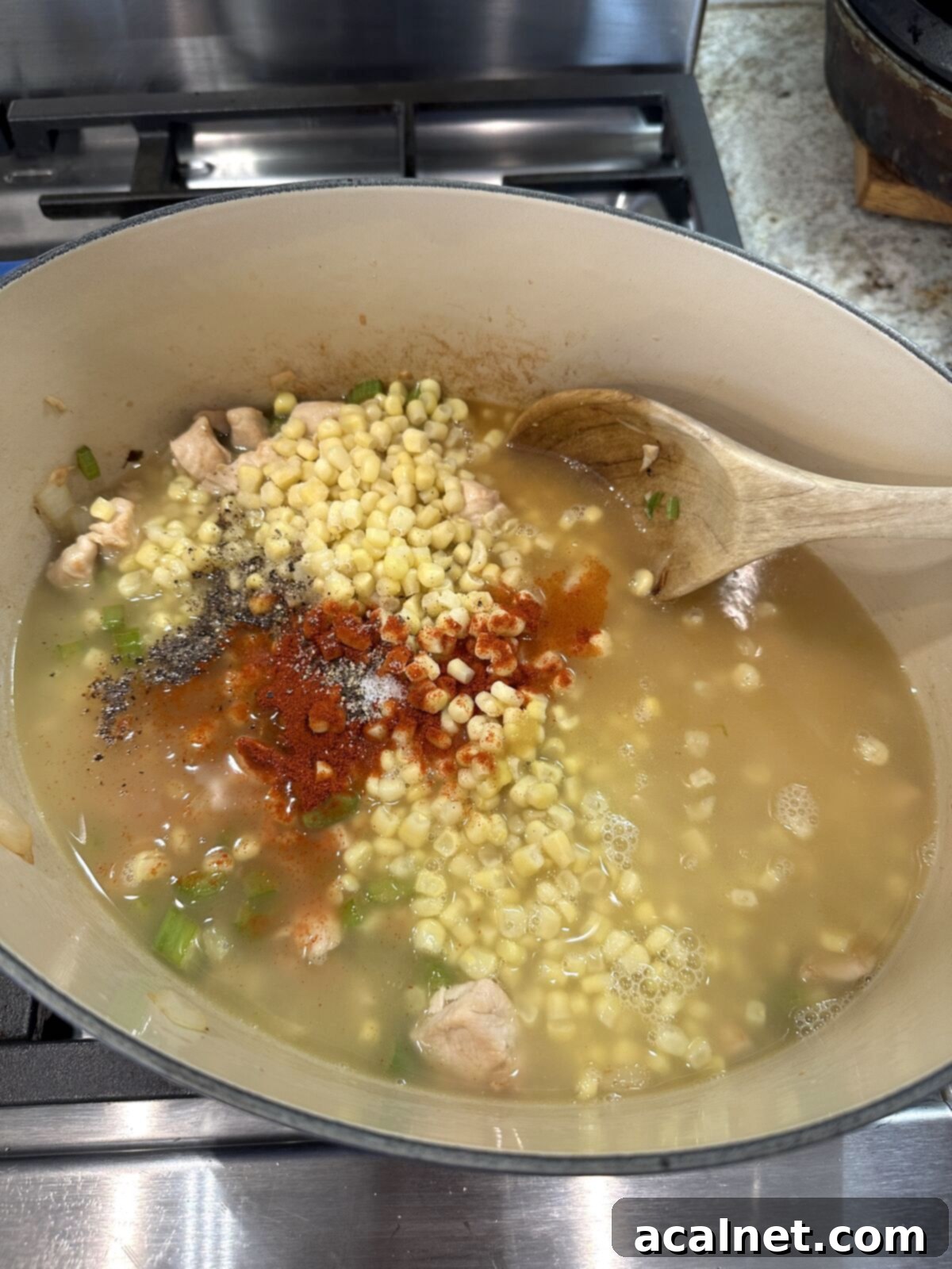 Golden Harvest Chowder 7 Whole kernel corn simmering with chicken broth and spices in a pan, filling the kitchen with inviting aromas.