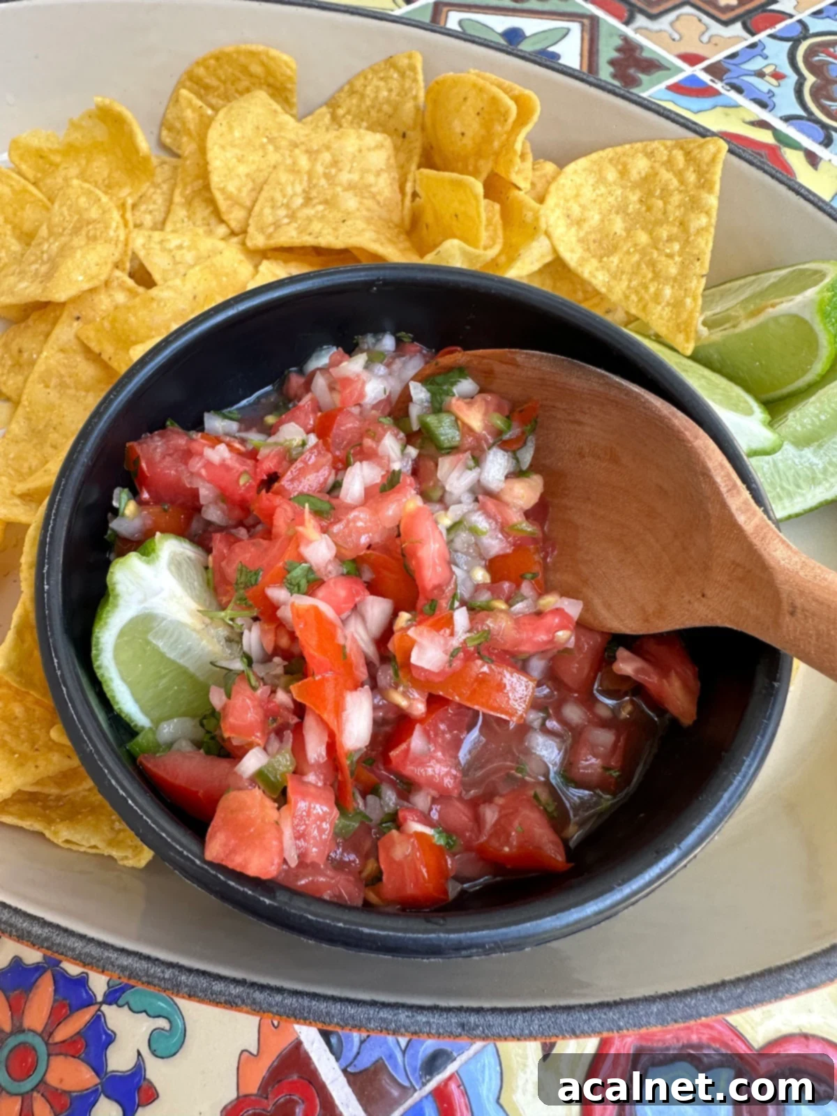 Zesty Jalapeño-Lime Pico de Gallo 11 A beautifully presented bowl of homemade pico de gallo with a side of crispy tortilla chips and fresh lime wedges, ready for enjoyment.