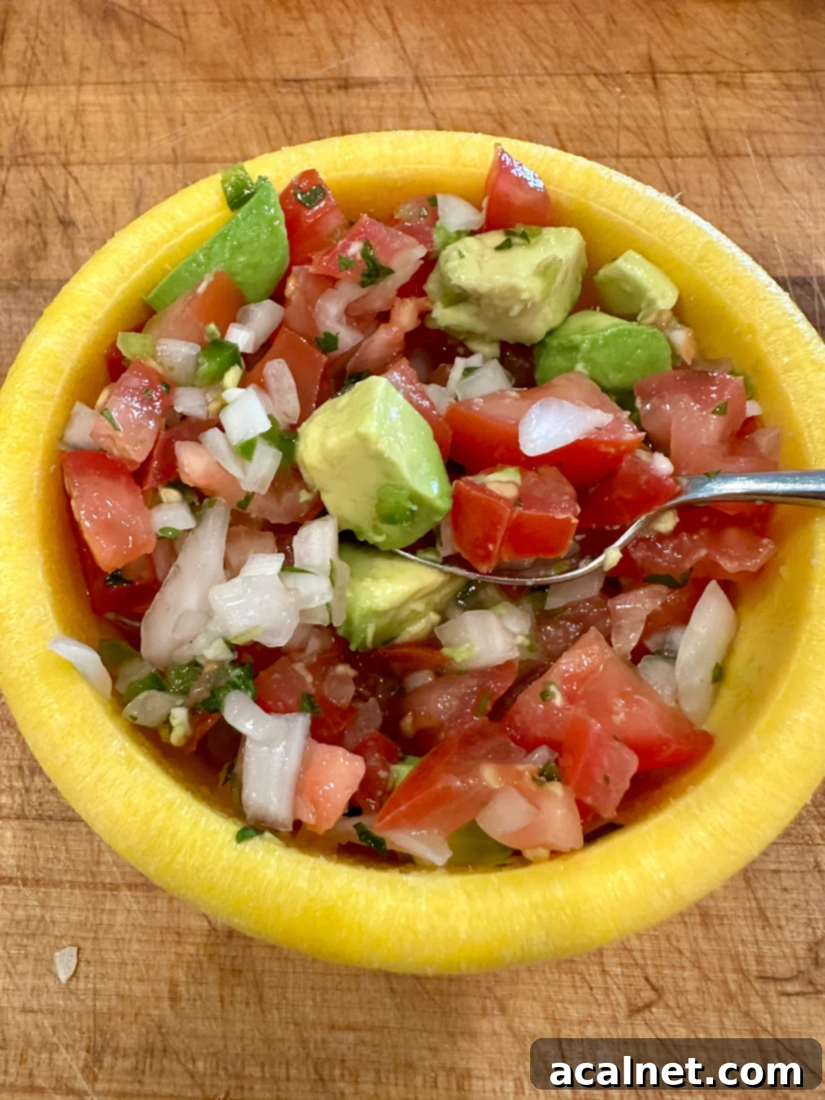 Zesty Jalapeño-Lime Pico de Gallo 5 A small, vibrant bowl of homemade pico de gallo mixed with creamy diced avocado, ready to be served.