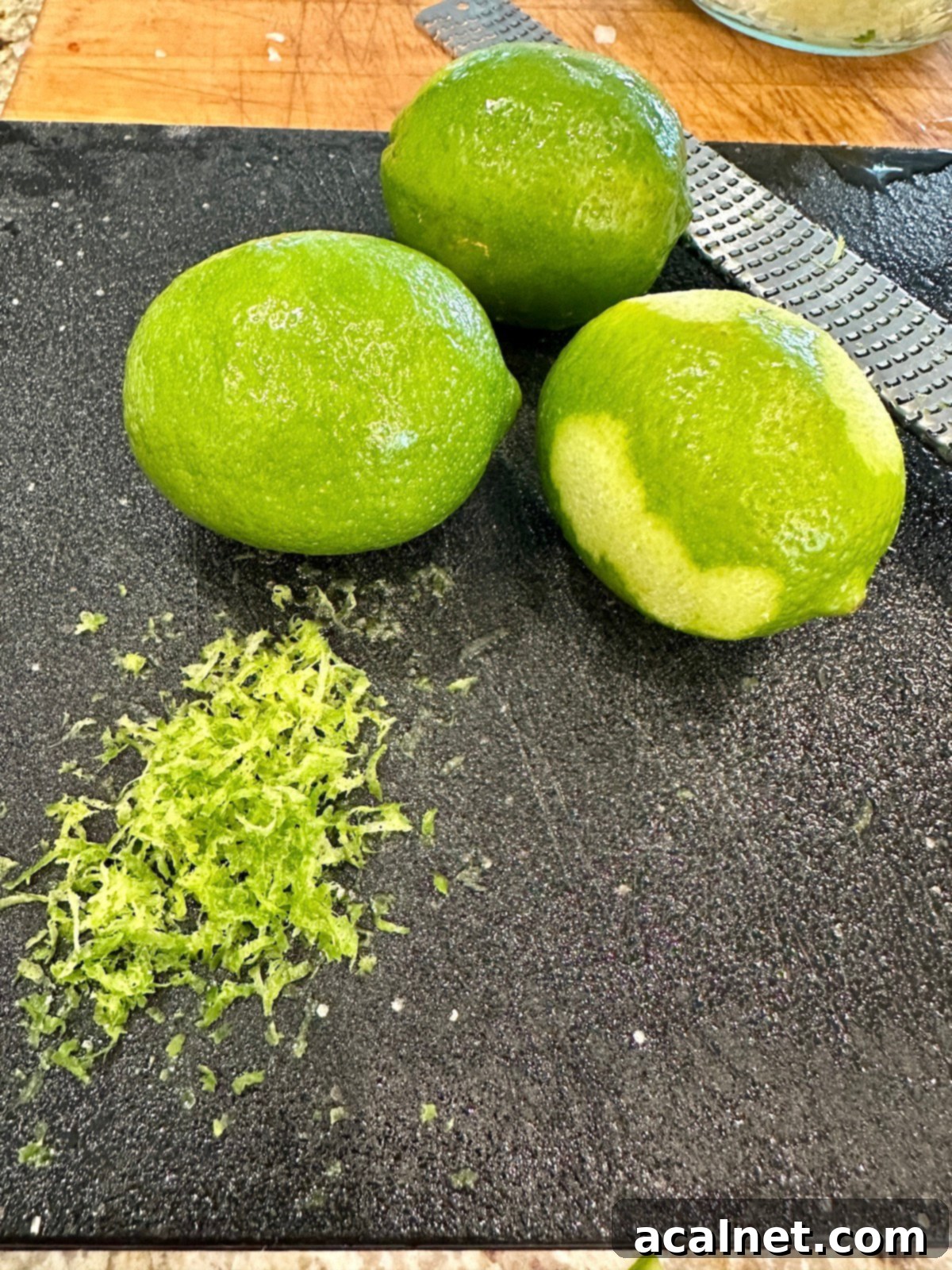 Zesty Jalapeño-Lime Pico de Gallo 9 Fresh, whole limes resting on a wooden cutting board, ready to be zested and juiced.