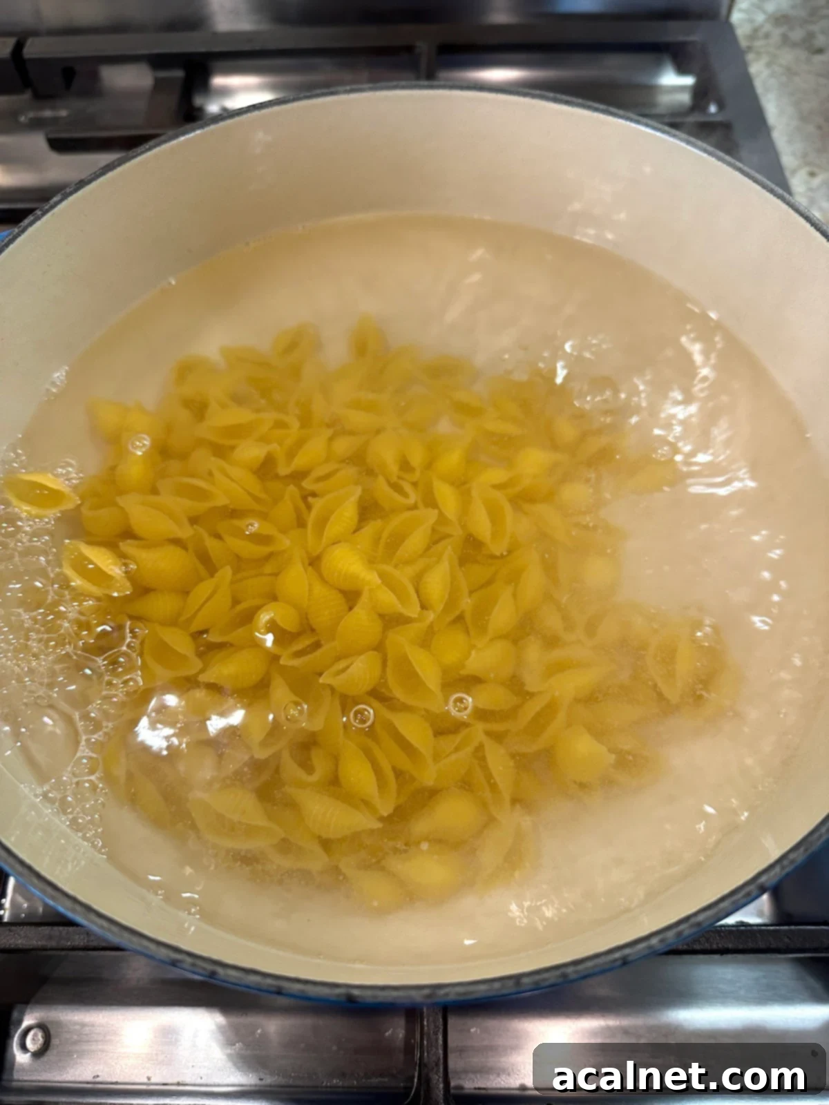 Pasta for salad in water in a pot on the stove.