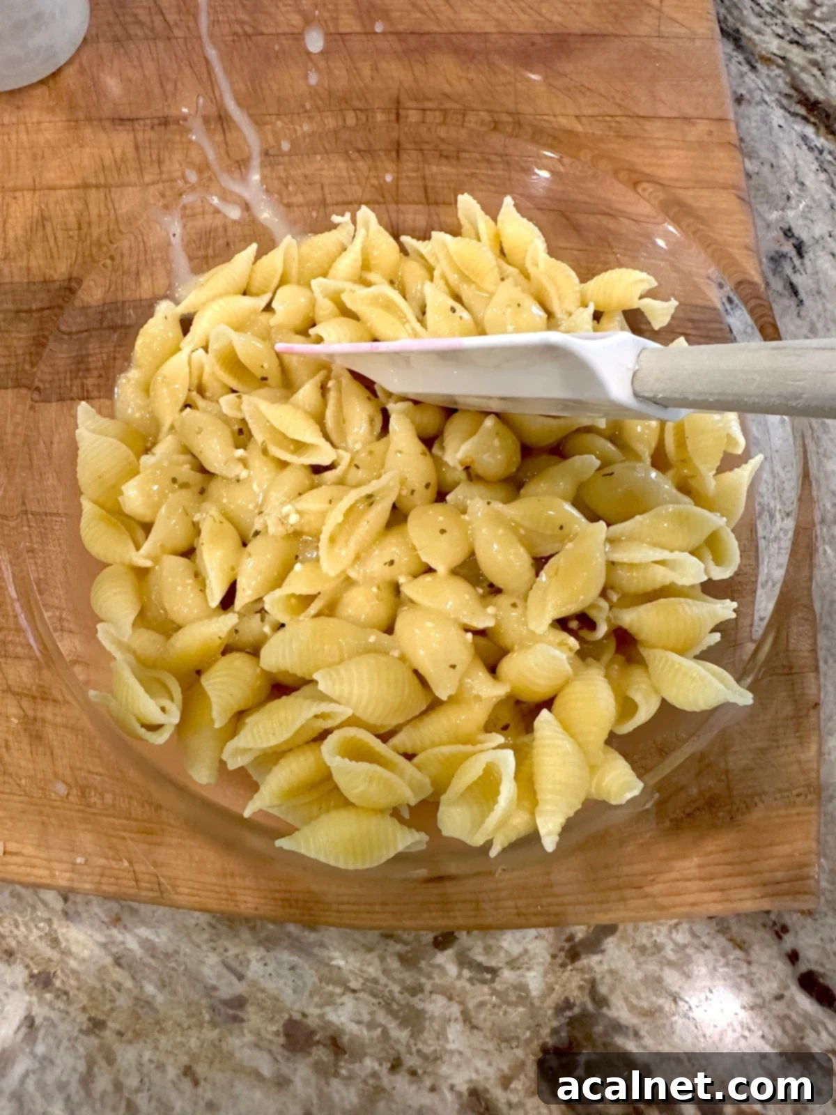 Cooked pasta with salad dressing in a bowl.